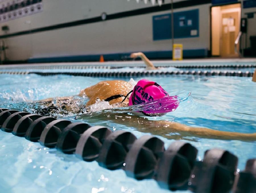A Nevada swimmer in the pool mid stroke with Wolf Pack swim cap