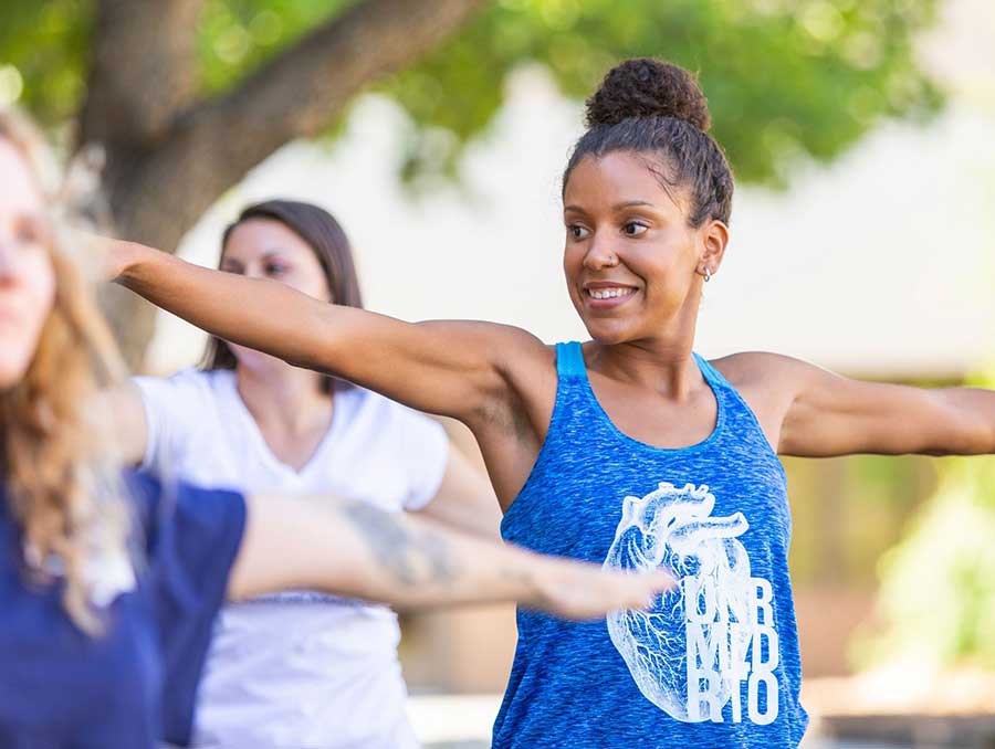 A Black woman in a UNR Med tank top warms up with other athletes before participating in the Reno-Tahoe Odyssey.