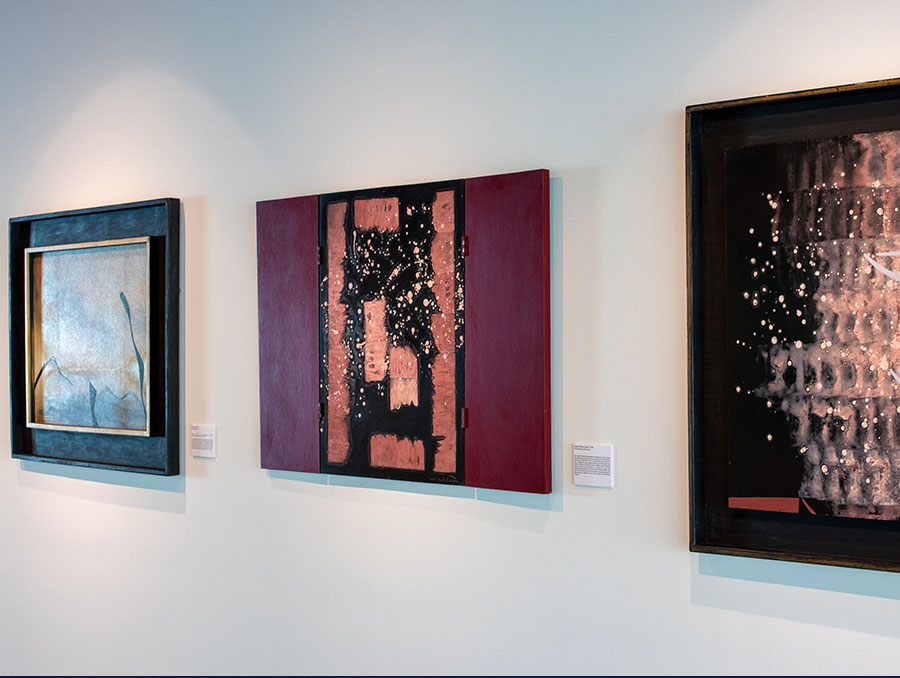 Three abstract oil pantings hang on an art gallery wall