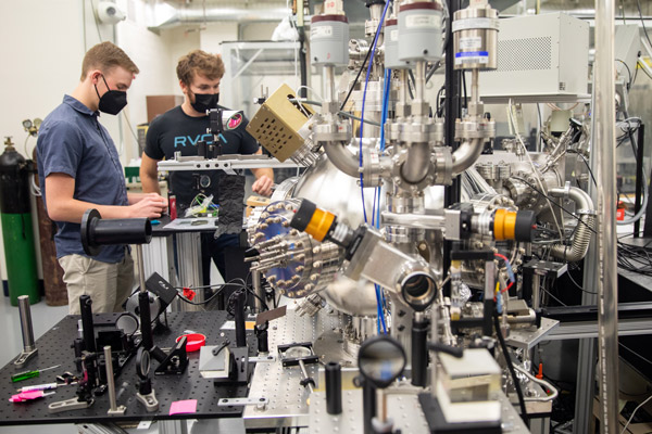 Armbrust (left) and Pattengale work in the lab, surrounded by large pieces of lab equipment.