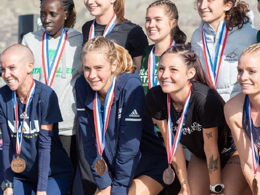 The Wolf Pack Women's Cross Country team posing with medals