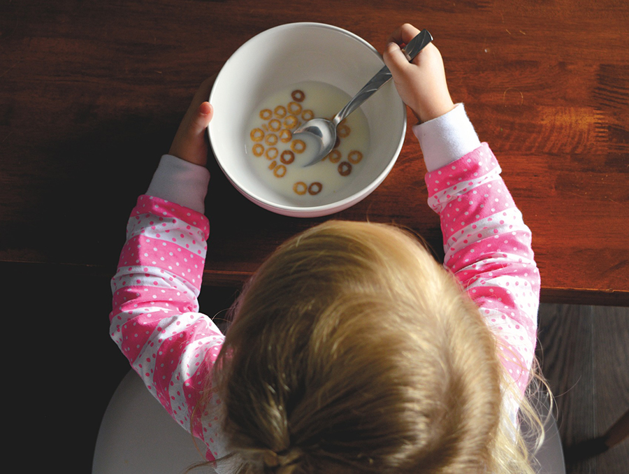 A child eating cereal in a bowl of milk.