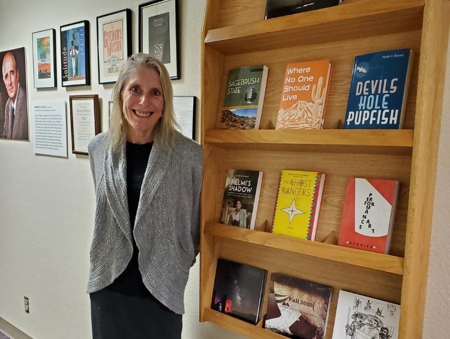 JoAnne Banducci standing near bookcase in Press hallway.