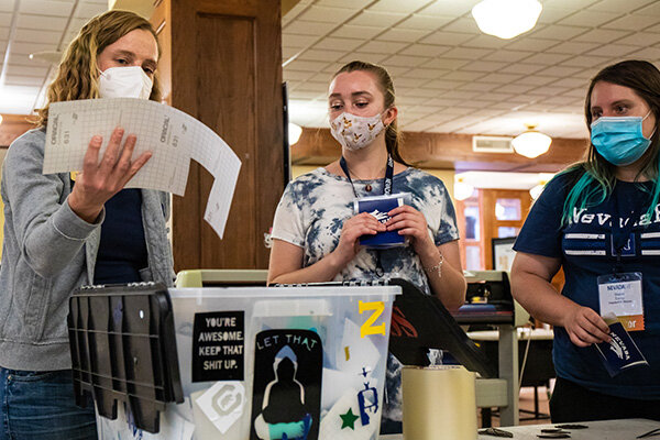 Three women standing around a table looking at a piece of adhesive vinyl created inside the DeLaMare Library’s makerspace.