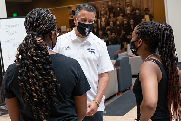 University President Brian Sandoval talks with two students standing in the atrium of the Mathewson-IGT Knowledge Center during the Aug. 2022 NOW Weekend which welcomed students and their families to campus.