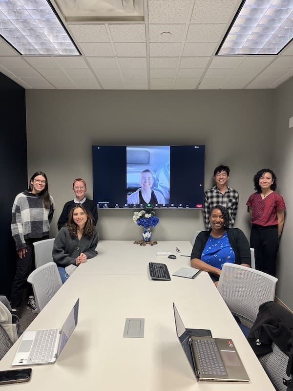 Group of students and Dr. Mitchell pose in a conference room