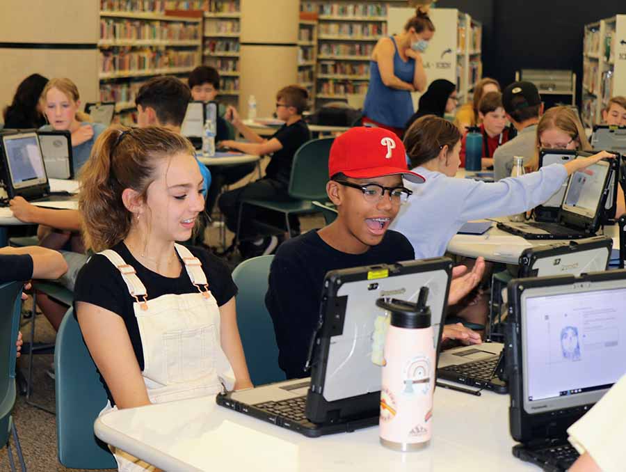 Two students working on math problems on their laptop during camp