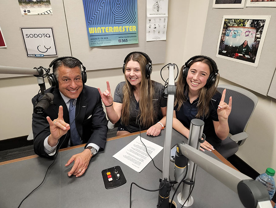 President Brian Sandoval, Dionne Stanfill and Bayla Fitzpatricj smile while sitting next to each other, wearing headphones in the recording space