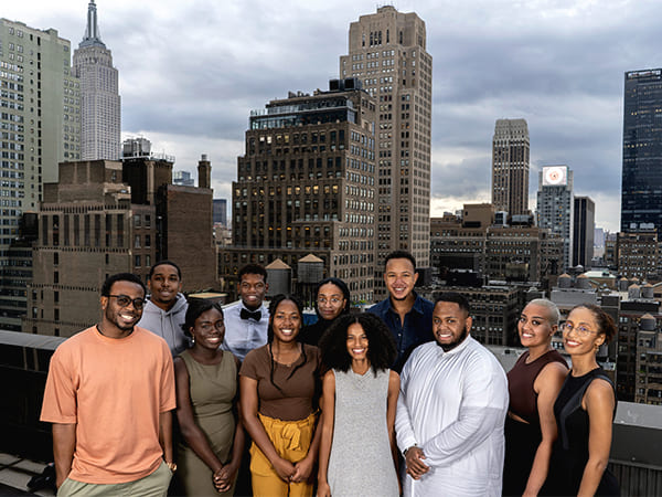 Taylor Johnson stands with a group of Ida. B Wells scholars in front of a New York City skyline.
