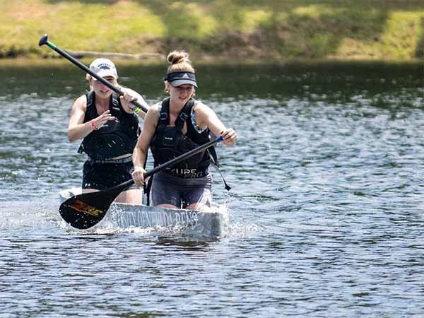 Two women paddling a canoe in a lake.