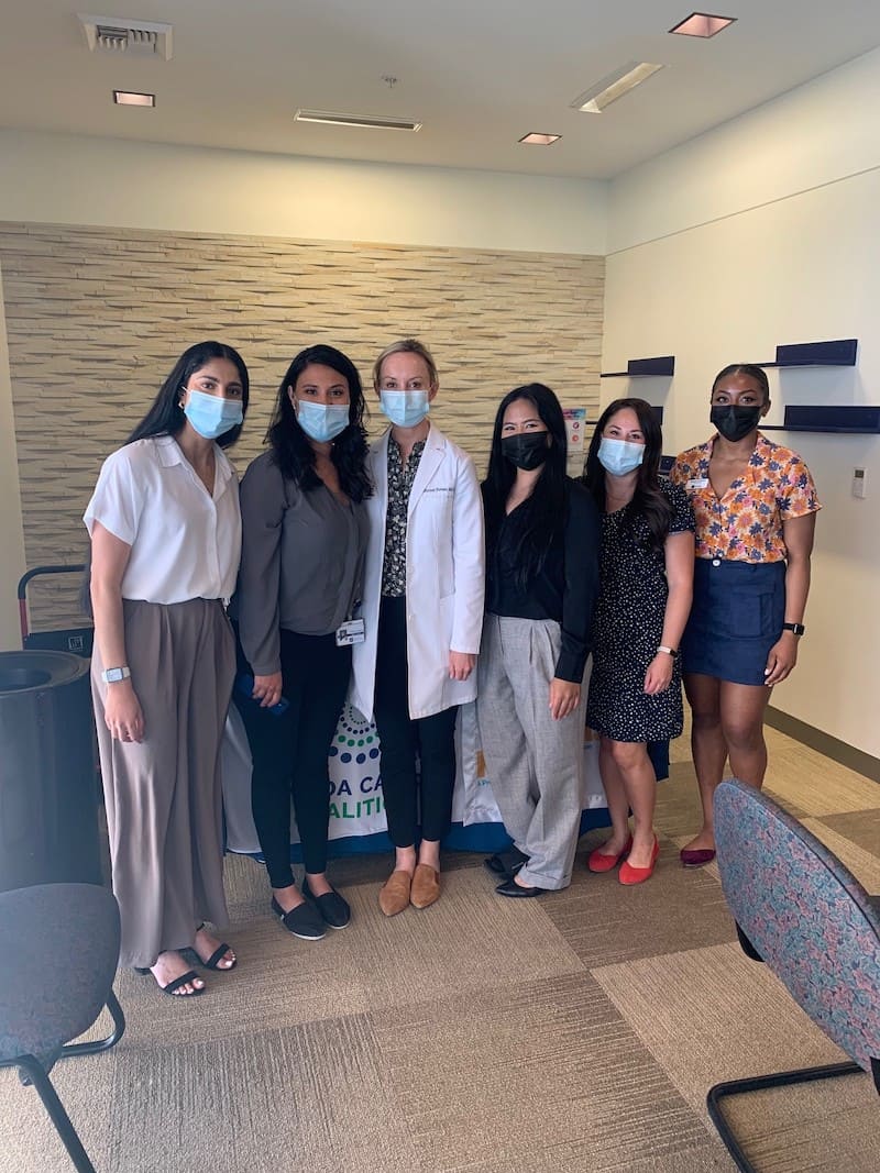 Ramneek Dhami and Lourdes Valdez posing with student volunteers and Dr. Whitney Hovenic from the Skin Cancer and Dermatology Institute (SCDI).