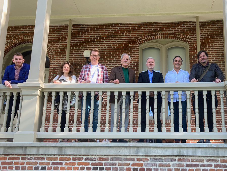 Group of individuals stand on balcony outside building