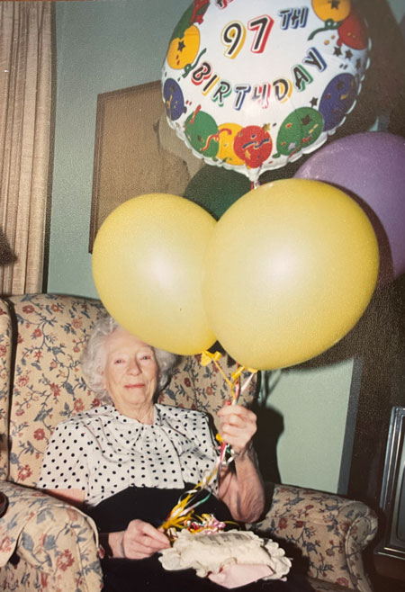 Elizabeth Durfee sits in a chair with balloons for her 97th birthday.