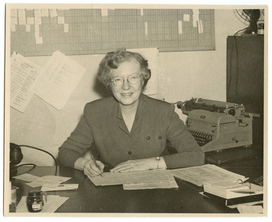 Elizabeth Racao Durfee smiles, working at her desk.