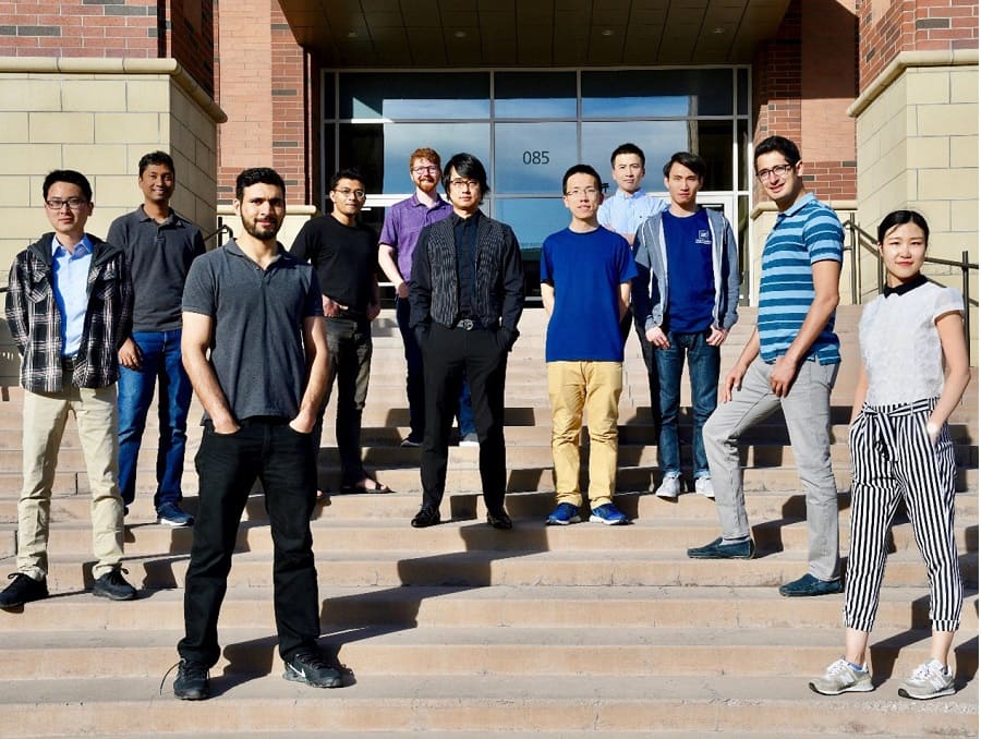 Professor Feng Yan standing on steps with 10 students