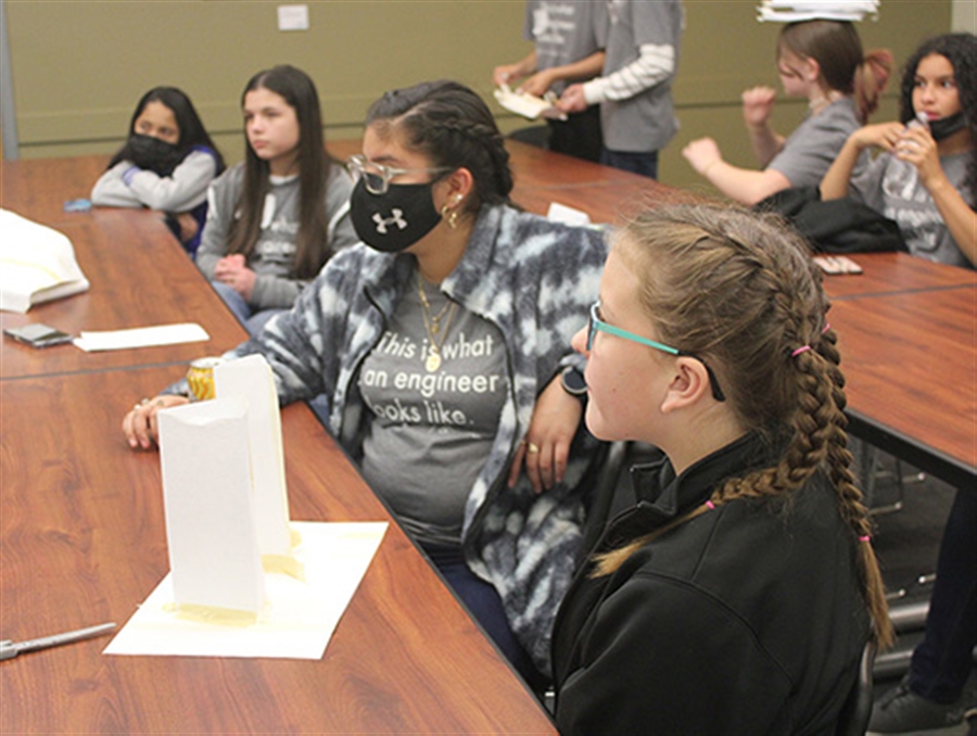 Middle-school girls at desks looking off-camera at instructor