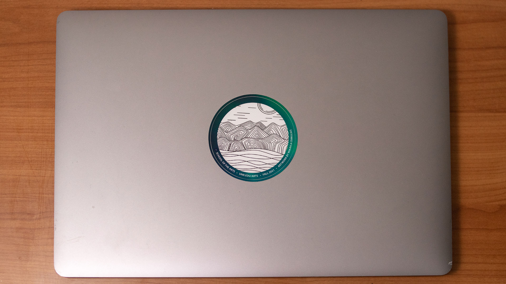 Fall 2021 sticker winner featuring sticker on laptop of illustration of mountains