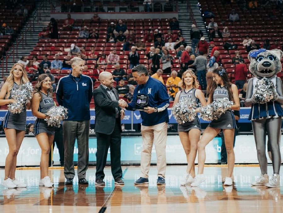 Wolf Pack cheerleaders with University President Brian Sandoval on the basketball court with the award