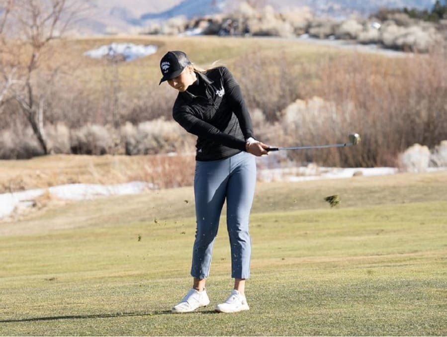 A member of the women's golf team swinging the club