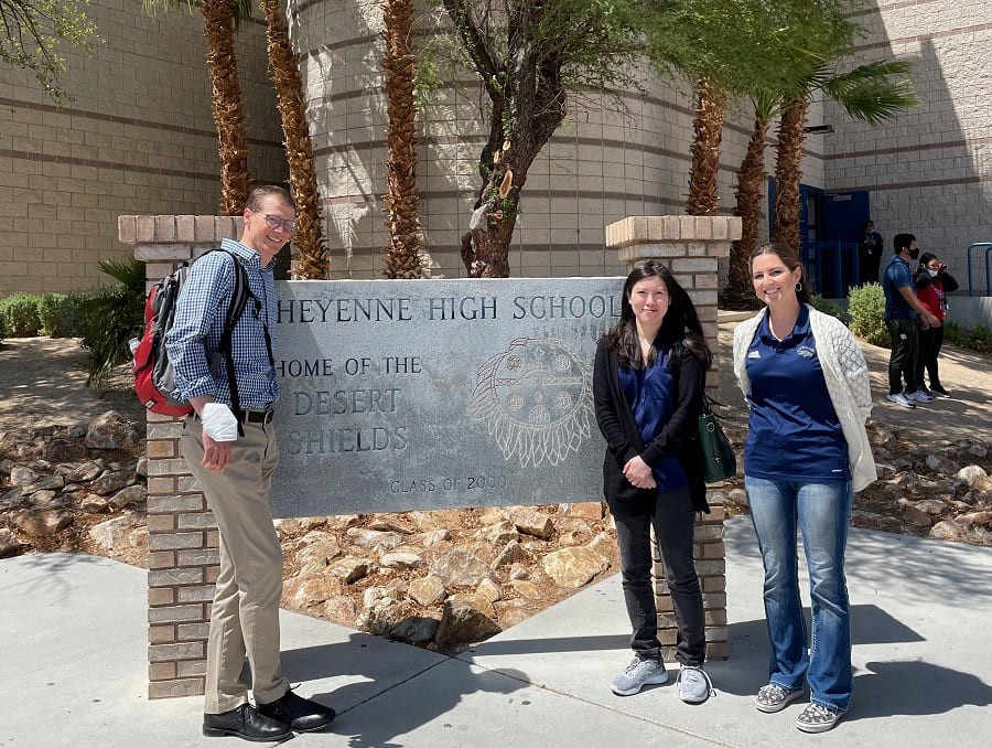 Jim Webber and Annie Trinh with Grace Bayer standing in front of the entrance sign at at Cheyenne High School.