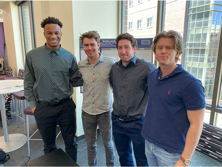 Four engineering students stand in front of a poster, window behind them.