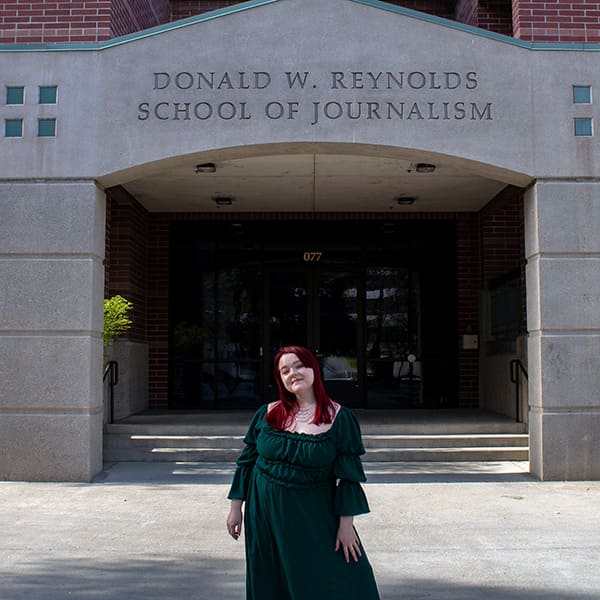 Catherine Schofield stands in front of the Reynolds School of Journalism building.