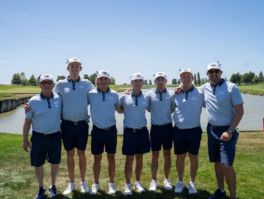 The Nevada Men's Golf Team posing in front of a lake on a golf course