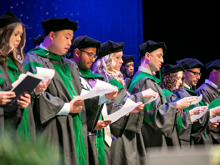 students on stage at the hooding ceremony