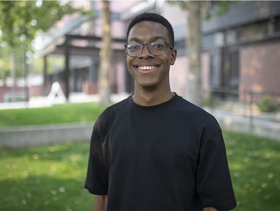 Tyreis Gatson standing outside, shown from the chest up, with a building in the background.