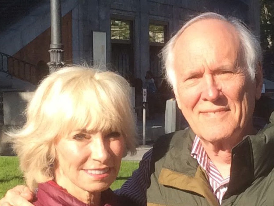 A woman and a man stand smiling in bright sunlight.