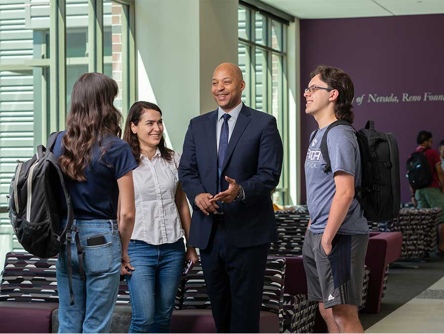 Dean Jones talking with a group of three students inside a building.