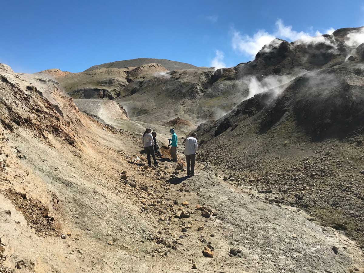 Four people hike up the valley with clouds collecting on the mountainsides nearby.