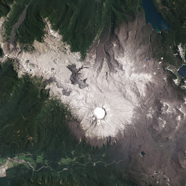 A satellite image shows a white circle surrounded by the light gray and green slopes of a volcano.