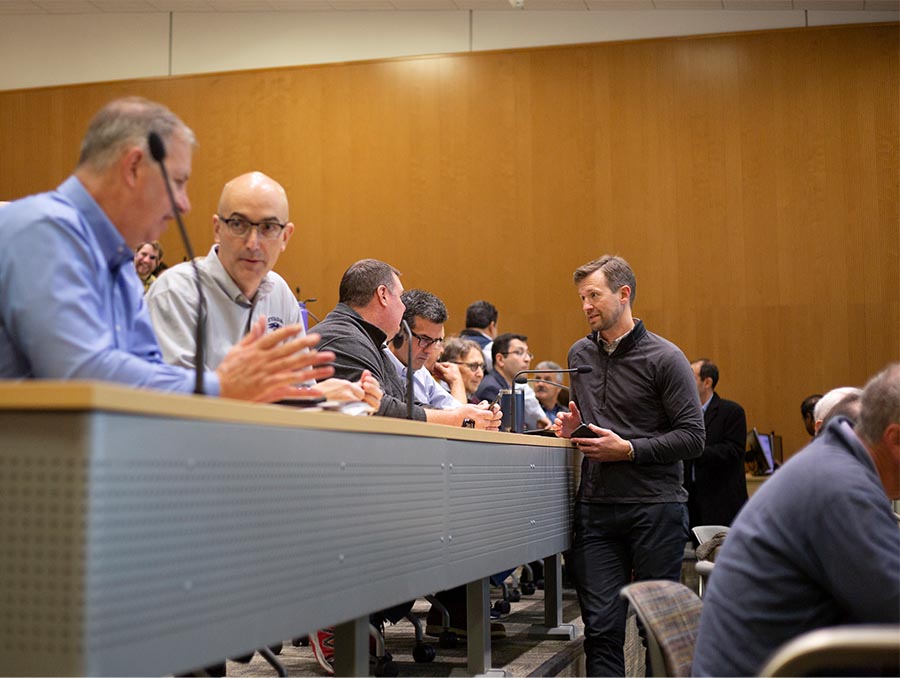 Nine people, seating and standing, in an auditorium.