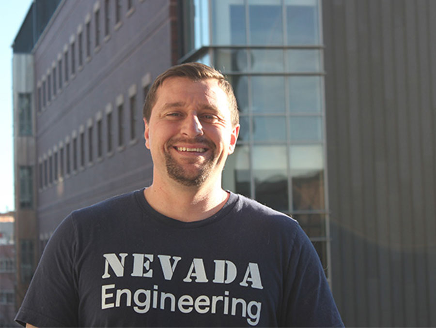 Alexander Silviera smiling, standing outside wearing a Nevada Engineering t-shirt.