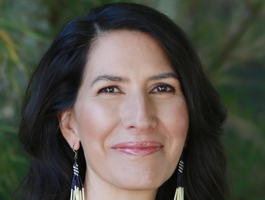 A headshot of Beth Piatote in front of a green background.