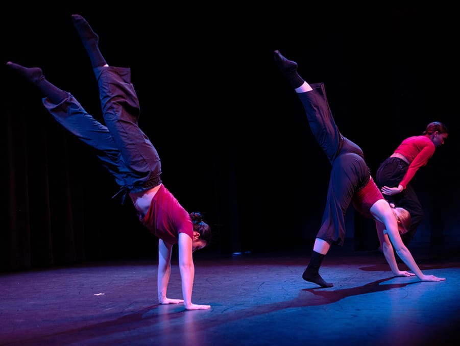 Dancers performing on stage and doing handstands.