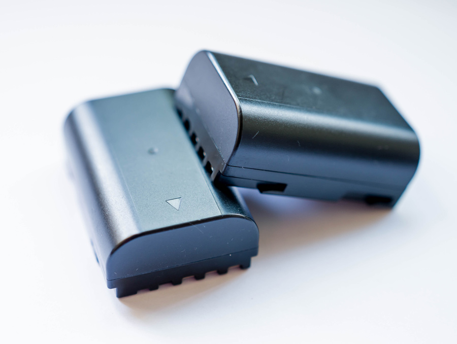 Two lithium-ion batteries, one leaning on the other, sit against a white background.