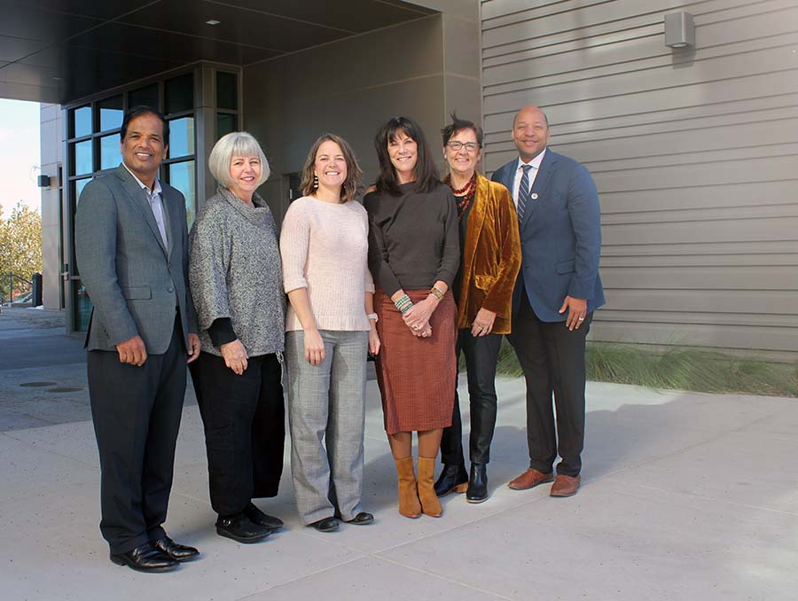 Six people standing outside in front of a building.