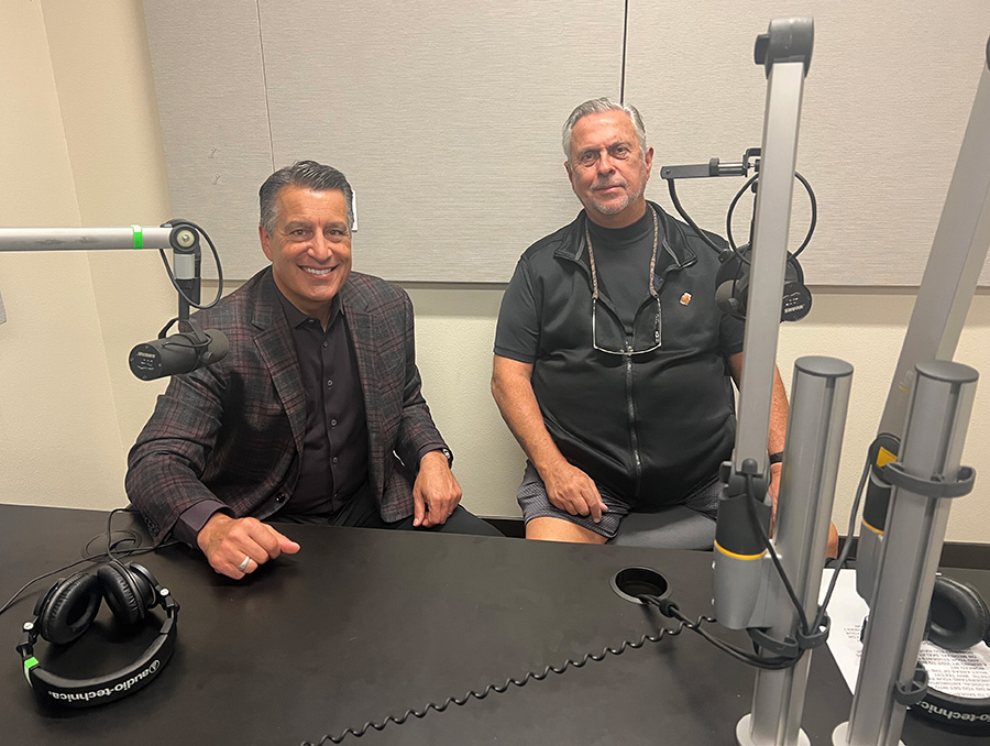 President Brian Sandoval and Dr. Richard Scott smile while sitting next to each other in the recording space