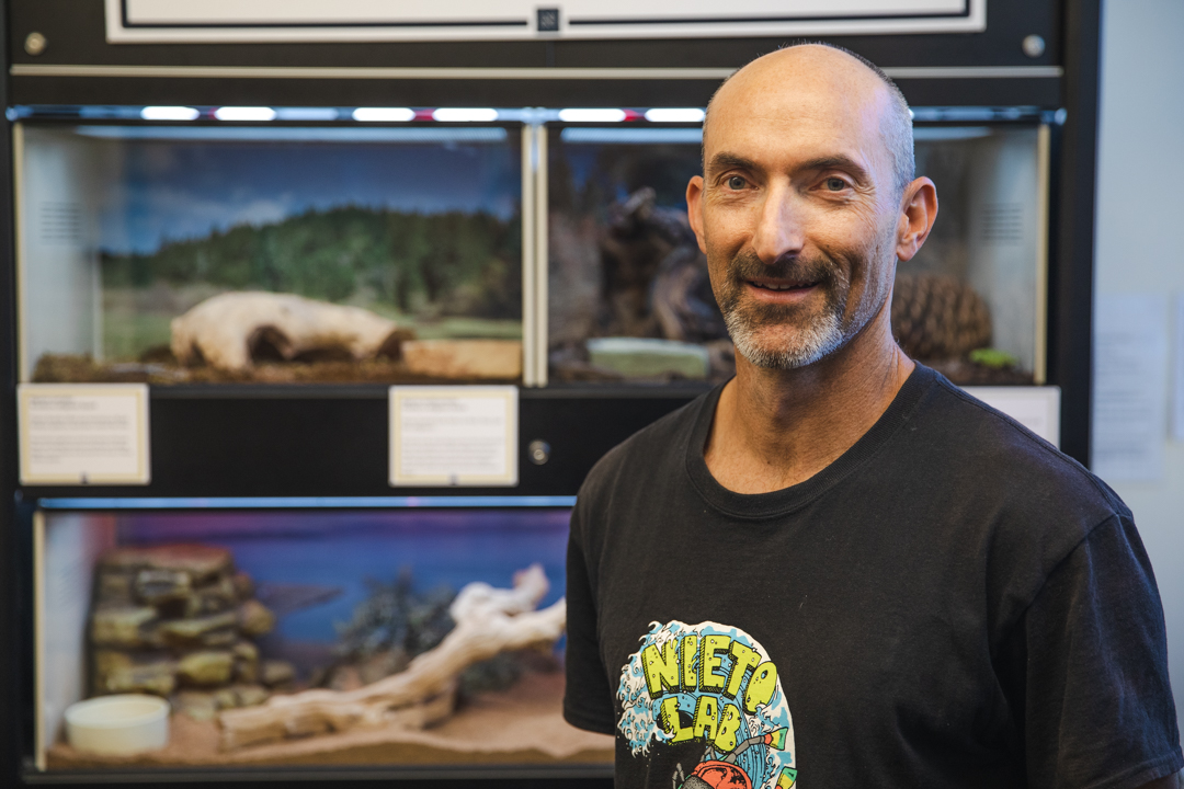 Chris Feldman in front of lizard terrariums