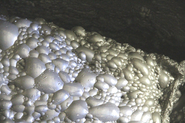 Bubbles forming at the surface of a silver liquid.