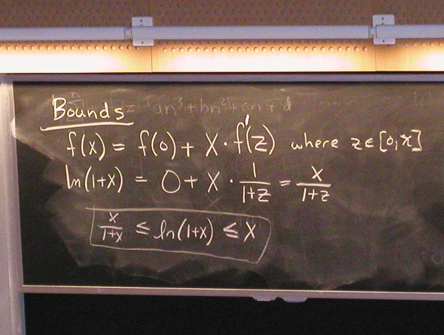 A hand writes math equations on a chalkboard with a white chalk marker.