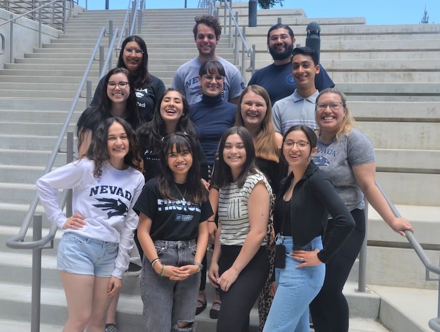 Group of students smiling closely together while standing on a staircase. 