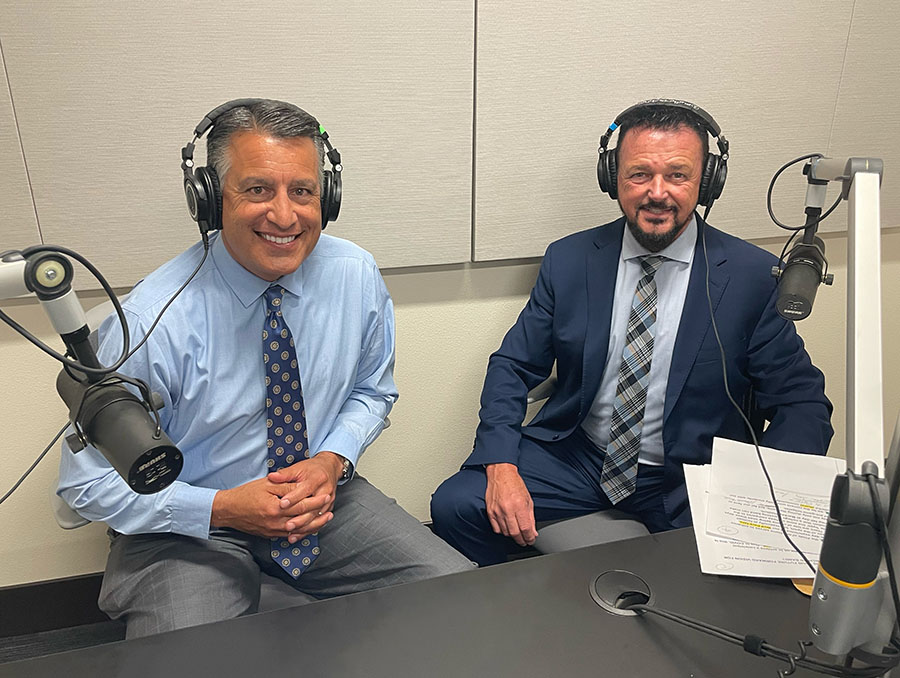 President Brian Sandoval and Dr. Steve Eubanks smile while sitting next to each other in the recording space