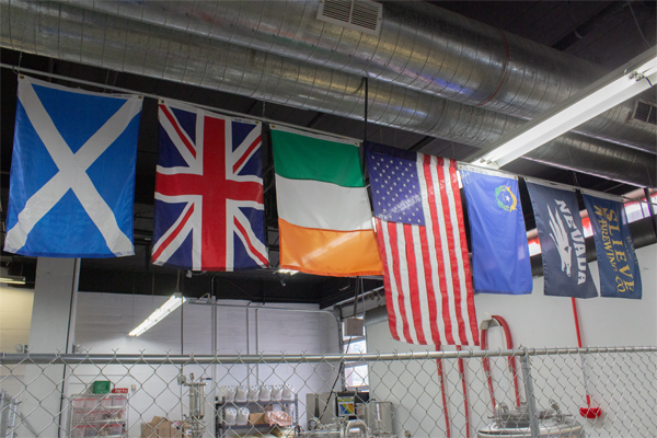 Flags from Scotland, the United Kingdom, Ireland, the United States, Nevada, the University of Nevada, Reno and Slieve Brewing Co. hang over the brewing section of the brewery.