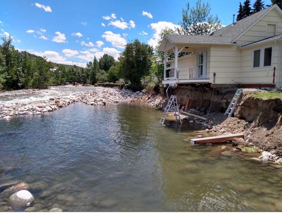 A house’s porch stands unsupported by the ground that used to lie beneath it.