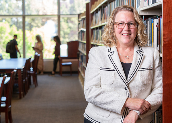 Dean Cardwell leaning against a stack of bookshelves inside the Mathewson-IGT Knowledge Center.