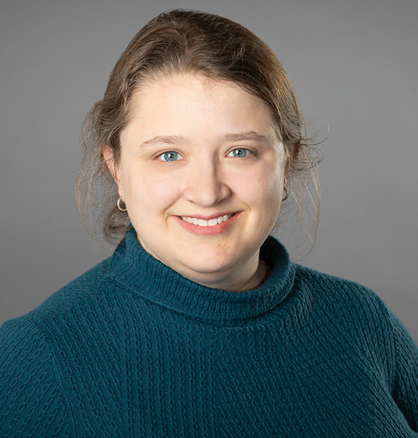 Portrait of Elspeth with her hair pulled back, wearing a dark green turtle neck sweater.