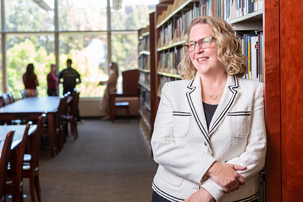 Dean of University Libraries Catherine Cardwell leans against the stacks located on the third floor of the Mathewson-IGT Knowledge Center.